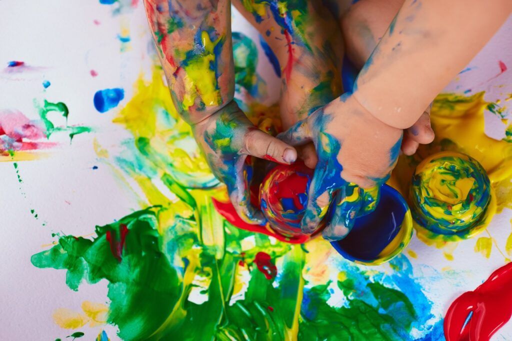 The small baby sits near different paints